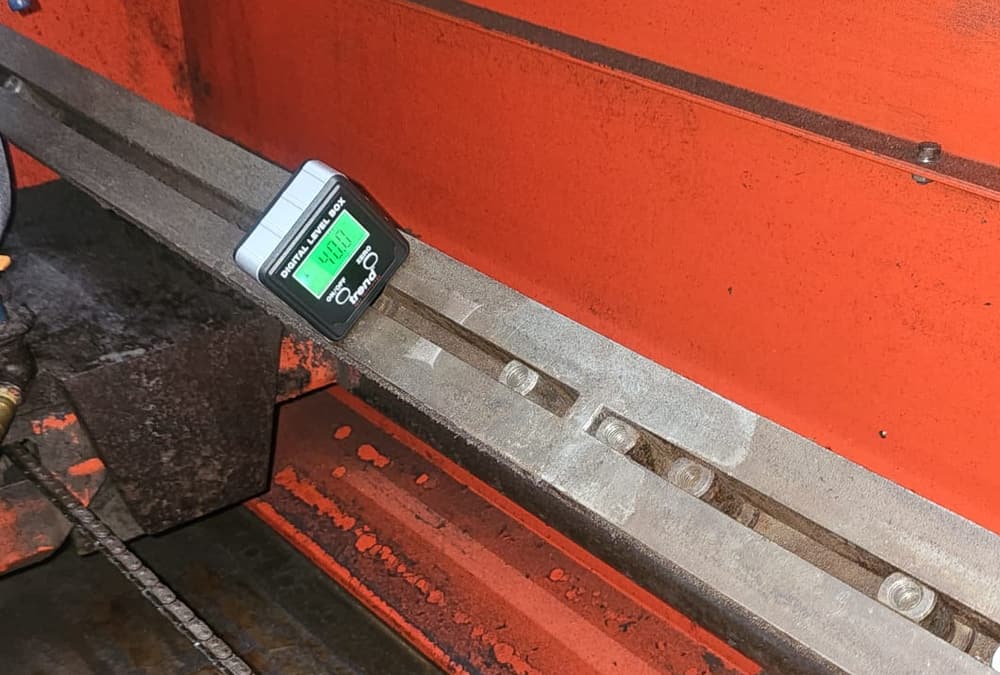 A digital angle gauge clamped to the blade rail of the Chippermaster grinder, its display reading 40.0 degrees